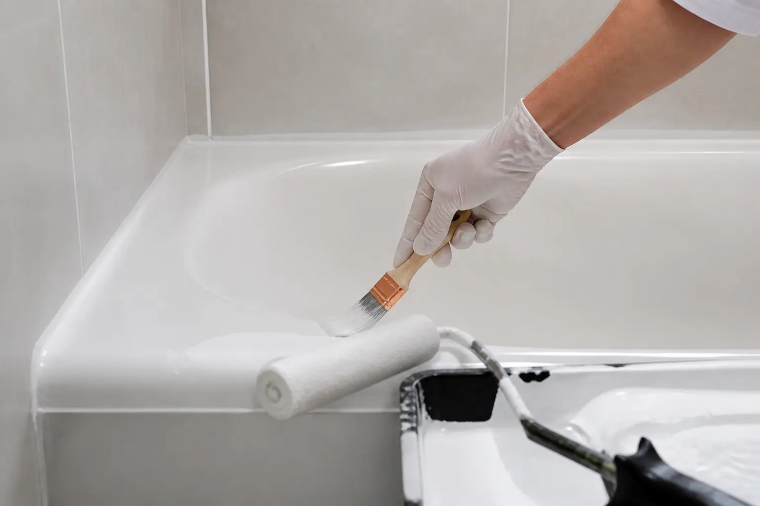Peindre la baignoire : application de la première couche sur les bords et angles avec pinceau et résine époxy.